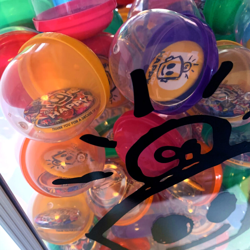 Closeup of HAPPY button vending machine capsules with custom buttons inside