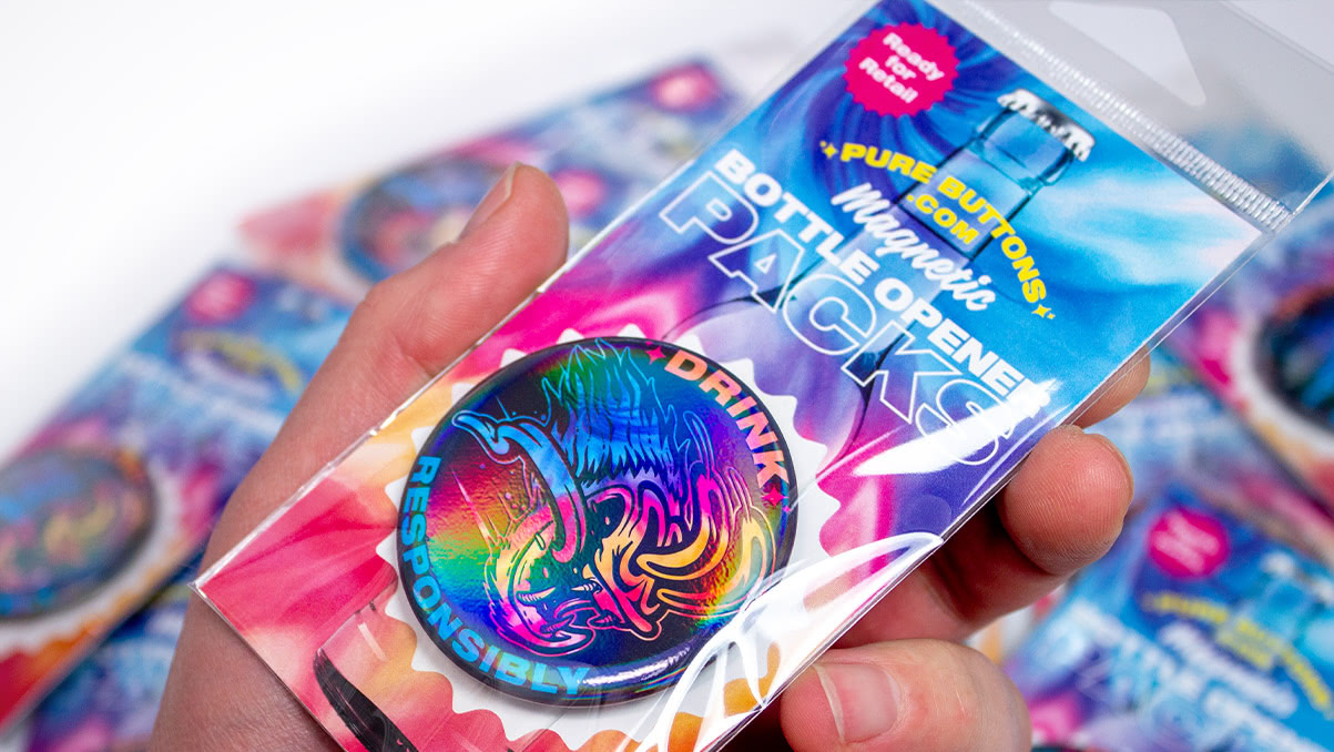 A hand holding a custom bottle opener with rainbow gloss finish inside retail packaging.