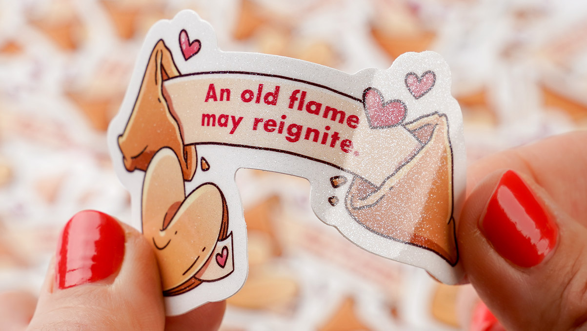 Hands holding a die cut glitter sticker shaped like a fortune cookie