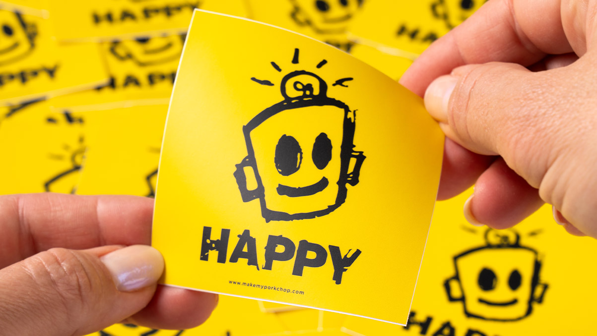 Hands holding a matte sticker that says HAPPY
